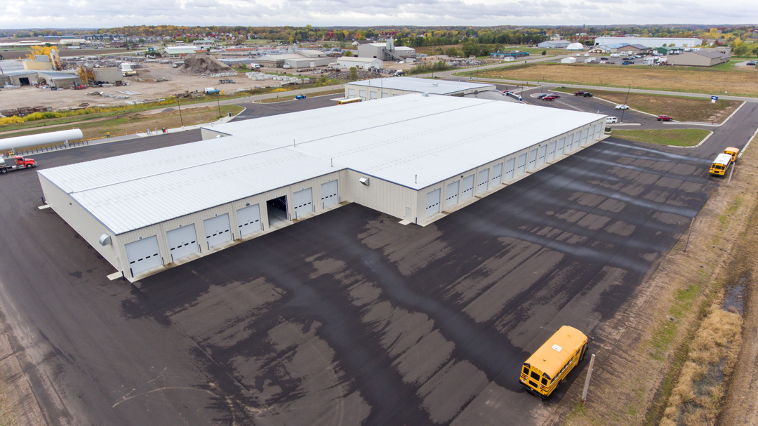 Aerial view of transportation facility showing bus storage building and paved lot, constructed by Rice Companies